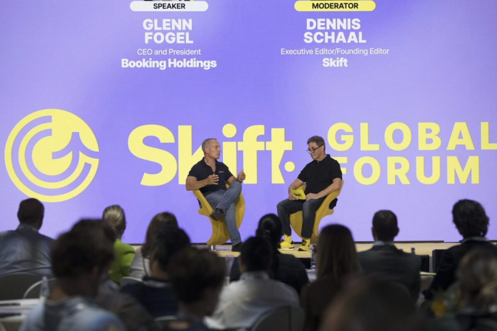 A crowd watching two men in a conversation on stage at an event.